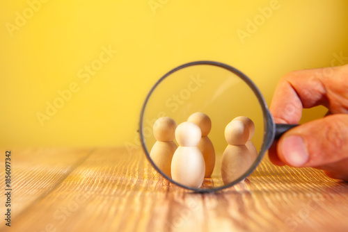 human figure holding magnifying glass in hand on wooden table