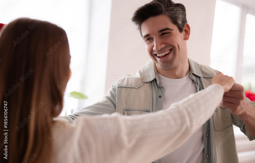 Obraz premium Happy young couple dancing together at home, smiling and enjoying quality time indoors. Romantic lifestyle moment, love, relationship, happiness, casual home interior. 