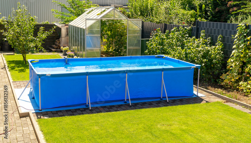 A large 2x4 meter swimming pool with clear water sits on a green lawn in the garden. A beautiful garden with a greenhouse and various plants provides a relaxing area for the whole family.