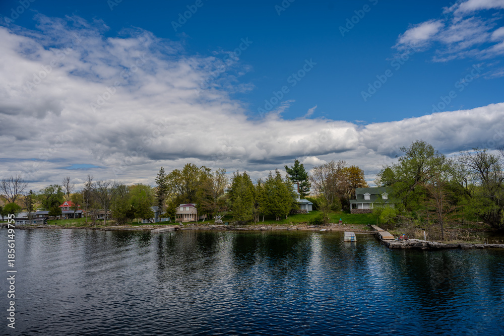 Fototapeta premium Lakeside cottages and trees under a cloudy sky