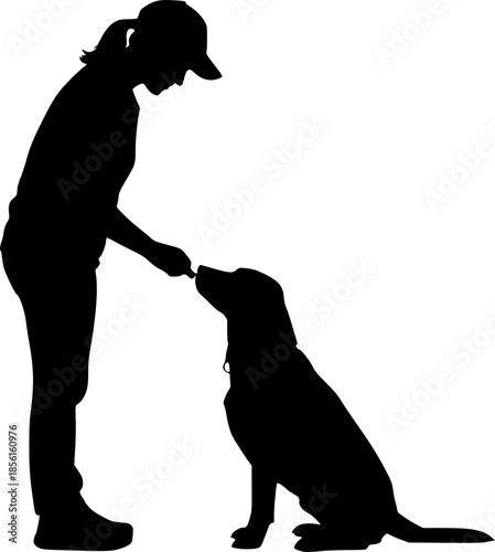 Silhouette of a person wearing a baseball cap giving a treat to a sitting black labrador dog on a white background
