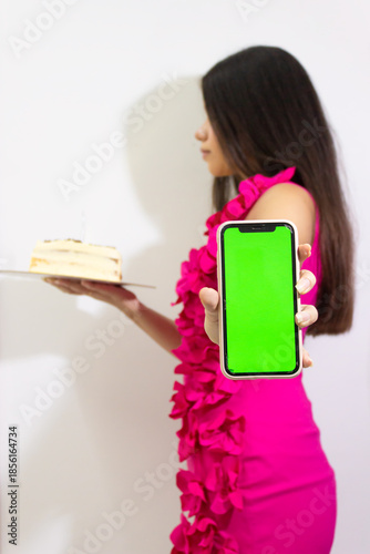 A young woman holding a cell phone with a green screen and chroma key