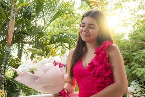 A young woman is holding a bouquet of flowers with trees in the background