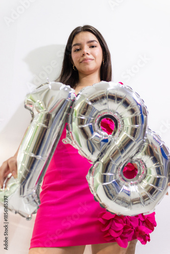 A young woman holding two plastic numbers against a white background
