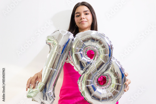 A young woman holding two plastic numbers against a white background