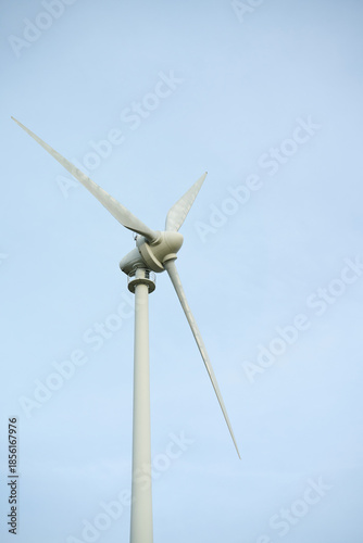 Wind turbine close up against sky. Close up of wind turbine with three blades against clear sky, viewed from below.