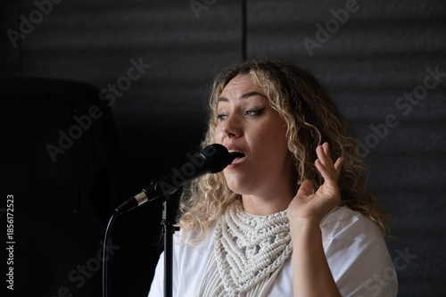 Caucasian woman singing into microphone in music studio. 