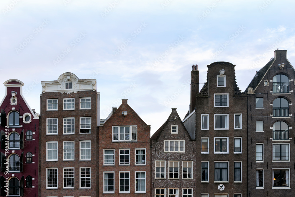 Naklejka premium Colorful Damrak canal waterfront houses, classic Dutch facades, famous travel destination. For tourist guides, travel blog visuals and social media posts
