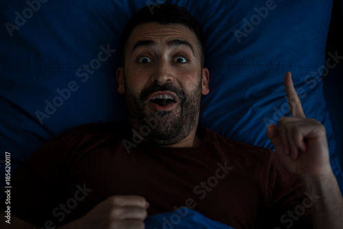 Photography Man having idea while sleeping at night, lying in bed, looking at camera