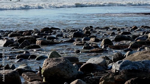 Video of shallow coastal water flowing over rocks on the beach in Ericeira, Portugal. Low tide with gentle movement, natural textures, ocean in the background, daylight conditions