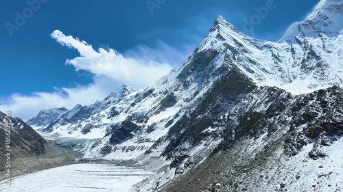 Majestic snow-covered mountains with jagged peaks and a glacier valley under a blue sky