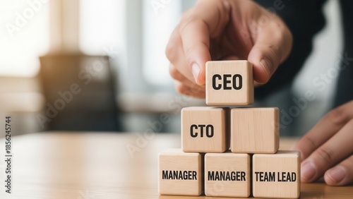 Wooden cubes representing leadership structure being positioned manually with fine shallow focus and softly diffused background