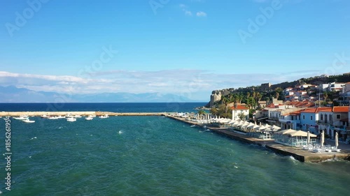 Wallpaper Mural Scenic view of the waterfront promenade, harbor with boats, and traditional buildings along the coast in Koroni, Greece, under a clear blue sky. Torontodigital.ca