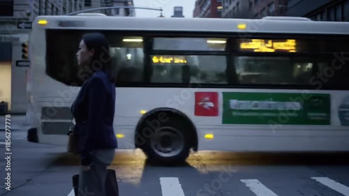 Asian woman standing on crosswalk on a city street with bus and buildings. Urban, people, crosswalk, street, city, bus, buildings.
