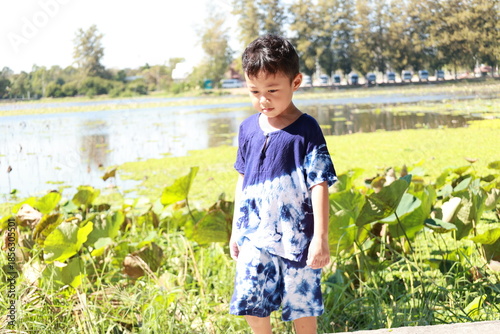 Portrait of a children in a park, A 3-year-old boy is happily walking in the park, wearing an Asian-style blue and white shirt.