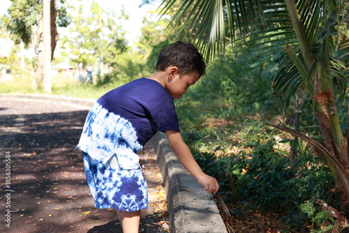 Portrait of a children in a park, A 3-year-old boy is happily walking in the park, wearing an Asian-style blue and white shirt.