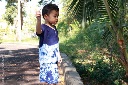 Portrait of a children in a park, A 3-year-old boy is happily walking in the park, wearing an Asian-style blue and white shirt.