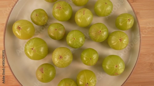 Indian gooseberry fruits on plate rotation top view. Amla. Phyllanthus emblica.