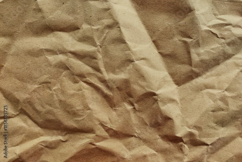 Crumpled brown kraft paper texture background with realistic wrinkles for sustainable packaging design and vintage aesthetic.