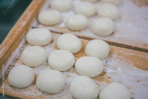 Close up of round white mochi rice cakes on a wooden surface