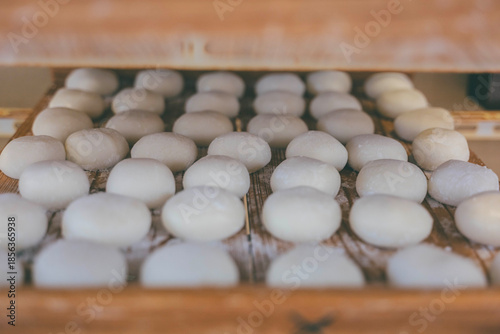 Freshly made white mochi rice cakes lined up on a wooden tray