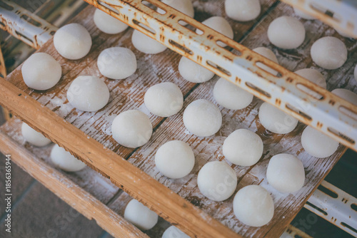 Fresh mochi rice cakes on wooden trays stacked in a cooling rack