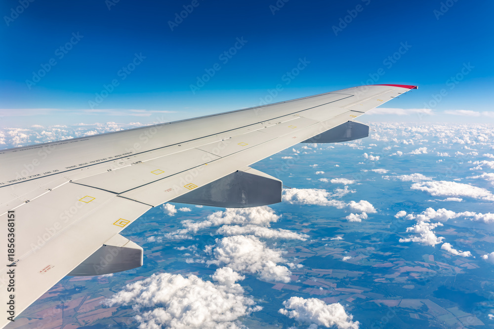 Fototapeta premium View from the airplane window at a beautiful cloudy sky and the airplane wing