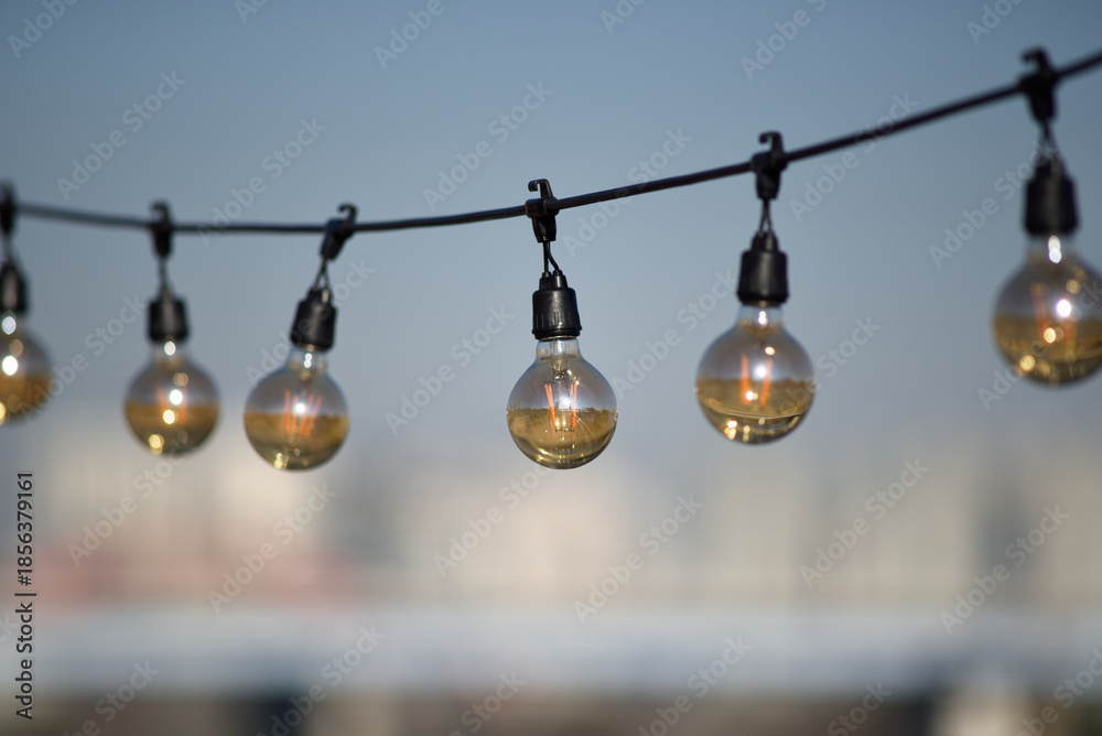 Obraz premium Hanging light bulbs against a blurred cityscape