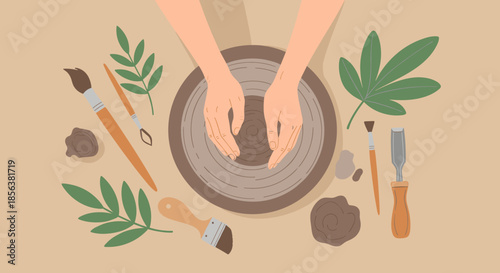 Top view of a person's hands shaping clay on a pottery wheel surrounded by various tools, leaves, and artistic materials.