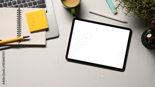Digital tablet on office desk workspace with, pen, laptop, flower and hot coffee cup on white table