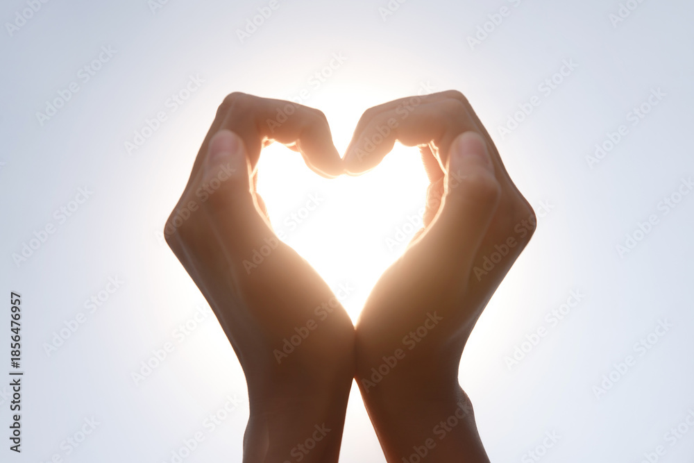 Fototapeta premium Hands Making Heart Shape Silhouette in Sunlight