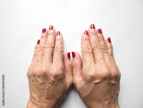 Female hands with red nail polish manicure on white background. Top view