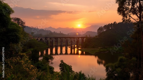 Serene Sunset Over a Majestic Bridge Reflecting in Calm Waters Surrounded by Lush Mountains and Scenic Landscape