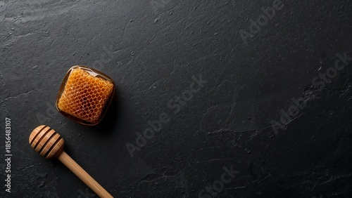 Raw Honeycomb and Dipper on Dark Stone Background with Copy Space.