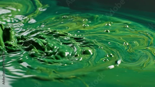 Extreme close-up of thick swirling green ink fluids creating slow motion organic abstract liquid waves and flowing turbulence psychedelic, waves, dynamic