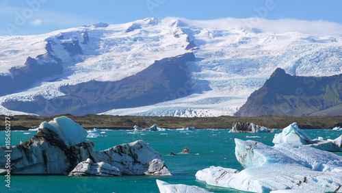 Obraz na plátne Massive glacier meets a glacial lagoon with floating blue icebergs under a blue