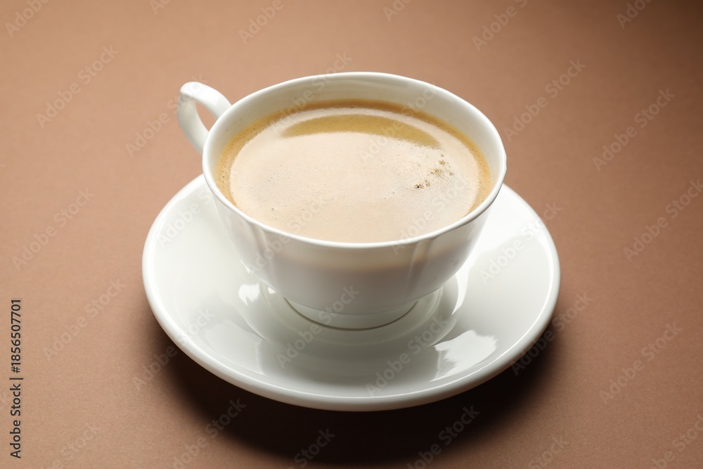 Fototapeta premium Aromatic coffee in cup on brown background, closeup