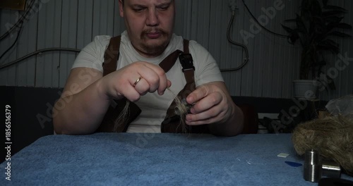 A professional plumber wraps the threads of a metal fitting with tow to ensure a watertight connection. The plumber carefully prepares the plumbing equipment for installation or repair.