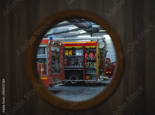 Quadro su tela Vue à travers un hublot de camions de pompiers rouges stationnés dans un garage