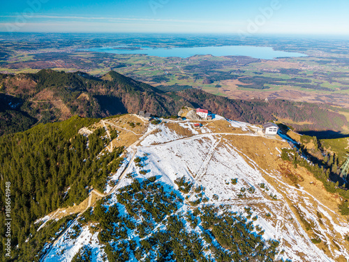 Top view to the Hochfelln mountain peak and the summit cross with a stunning landscape down to the valley of the Bavarian Chiemgau