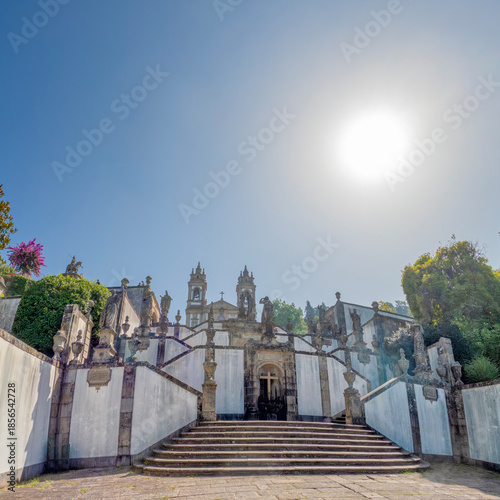 Baroque staircase of Bom Jesus do Monte Sanctuary in Braga, Portugal, with statues and church towers under a clear blue sky
