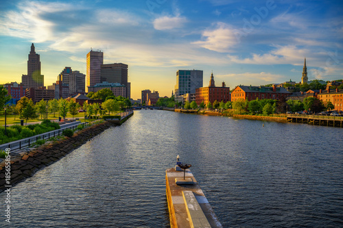 Sunset view of downtown Providence and the Providence River in Rhode Island, USA, with city buildings and New England riverside greenery.