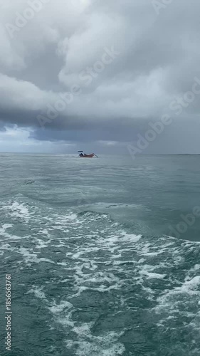 Vertical shot of a traditional wooden boat sailing on the turquoise ocean. Essential inter-island transportation and local maritime lifestyle in a tropical archipelago.