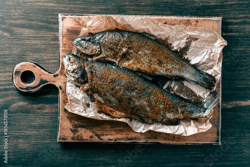 Delicious baked trout fish with spices on a cutting board, closeup, top view