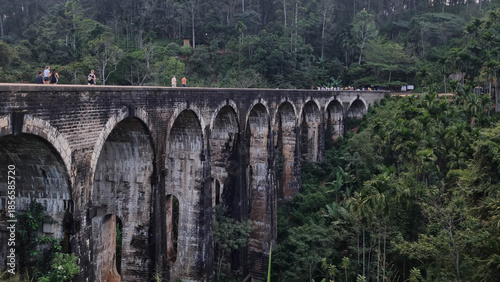 Ella, Sri Lanka March 05th 2025: Close-up and ground views of the Nine Arch Bridge with people walking along the railway track surrounded by lush forest.