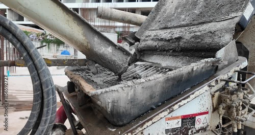 wet concrete pouring from a mixer chute into a pump hopper.