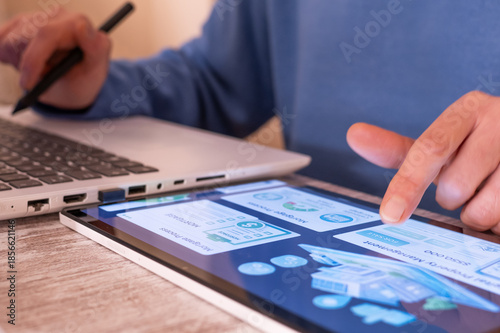 Foto Person using a digital tablet with real estate application interface and a lapto