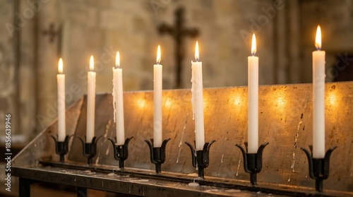 Row of burning prayer candles in a church. Spiritual faith and religion concept with blurred crucifix background