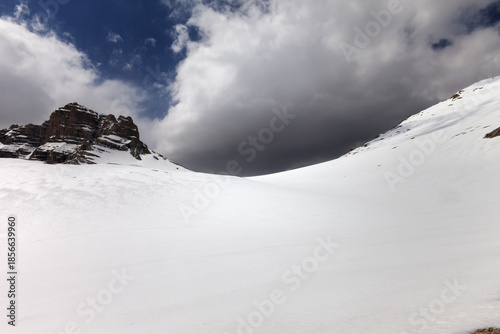 Snowy mountain pass and sky with storm clouds