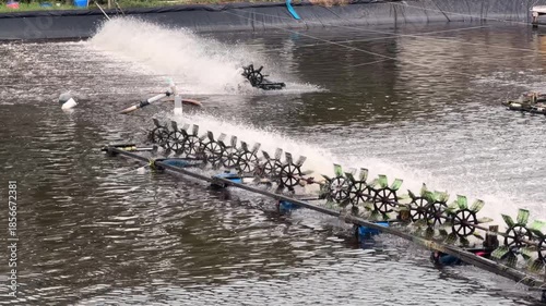 Panoramic view of multiple aerators working across a large pond, subtle waves spreading across the water. Large pond aeration.